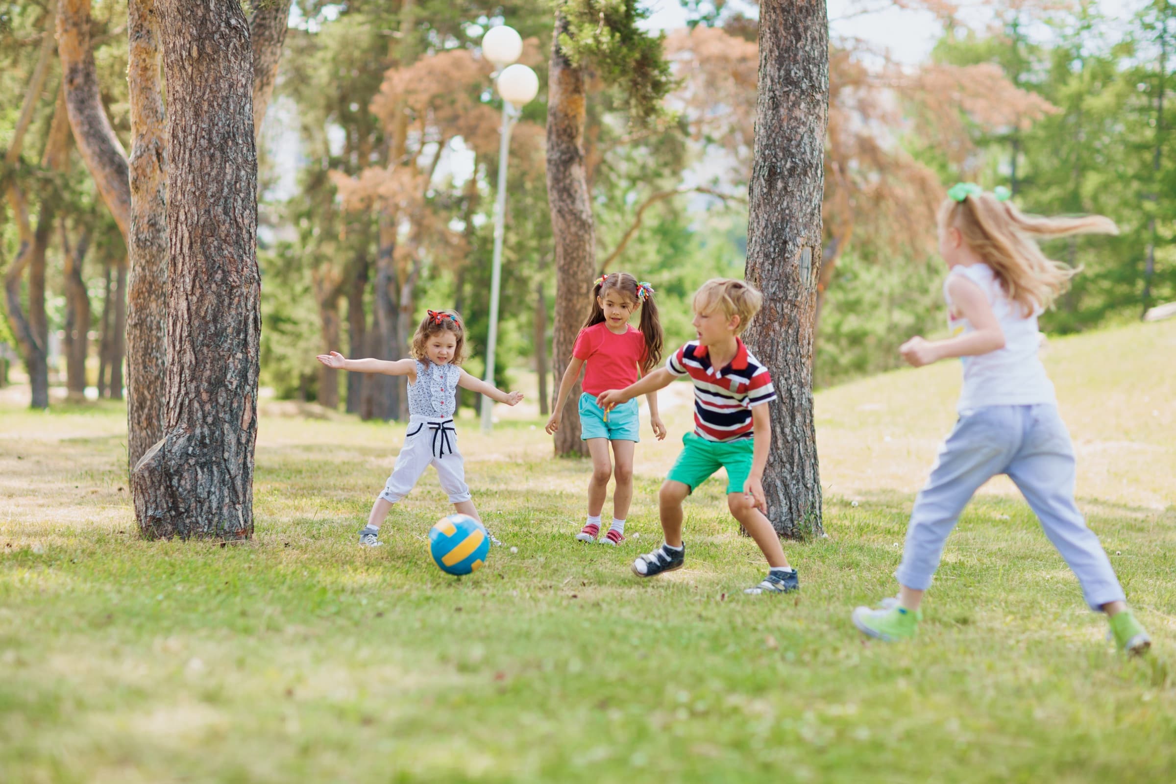 Children playing soccer on the grass in a park